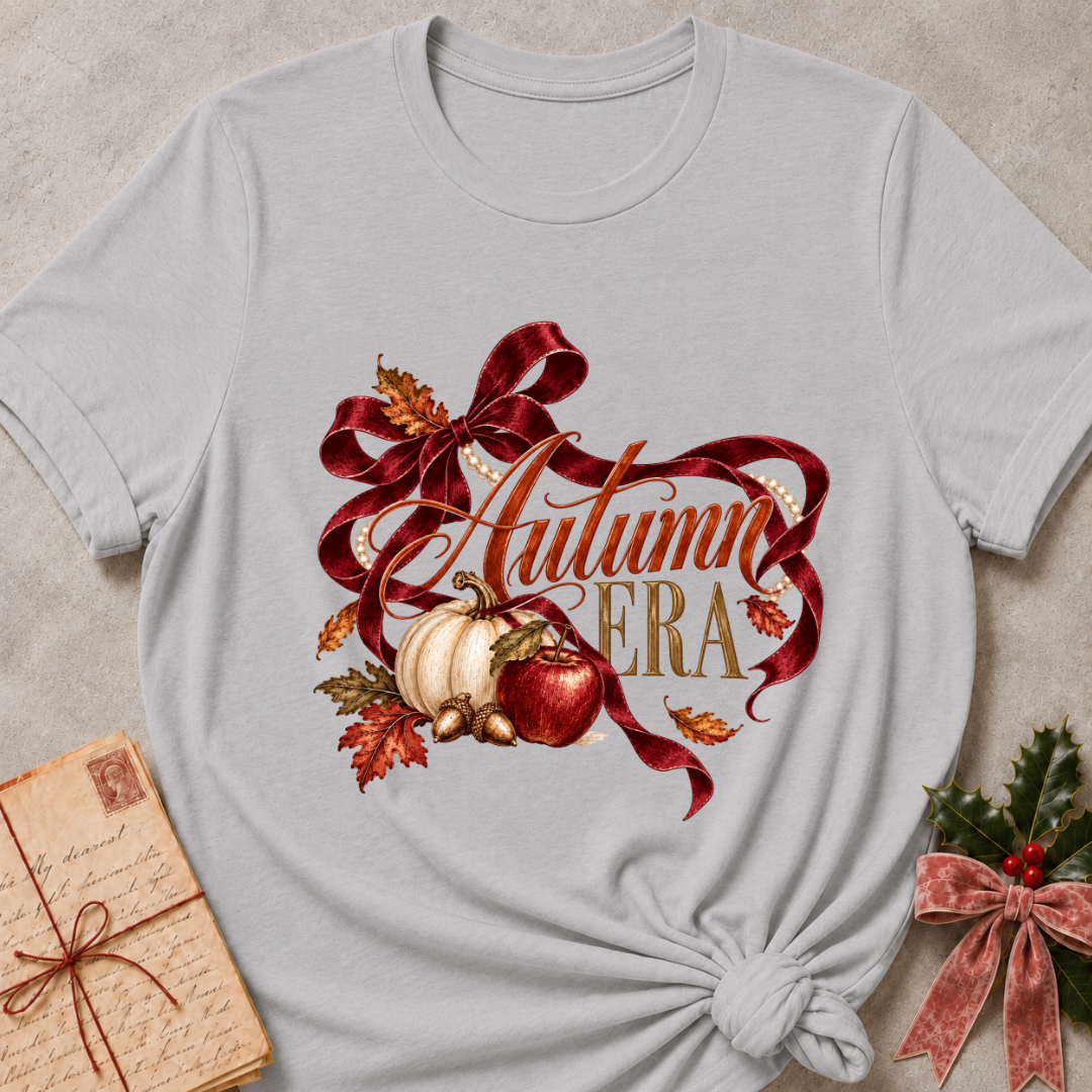 Athletic heather grey women's relaxed tee with Autumn Era script framed by a burgundy ribbon, pearls, a cream pumpkin, a red apple, and fall leaves