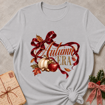 Athletic heather grey women's relaxed tee with Autumn Era script framed by a burgundy ribbon, pearls, a cream pumpkin, a red apple, and fall leaves
