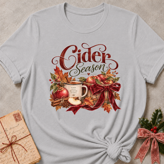 Athletic heather grey women's relaxed tee with a Cider Season script design with a cider mug, red apples, cinnamon sticks, and a burgundy ribbon bow