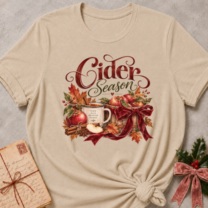 Heather stone women's relaxed tee with a Cider Season script design with a cider mug, red apples, cinnamon sticks, and a burgundy ribbon bow