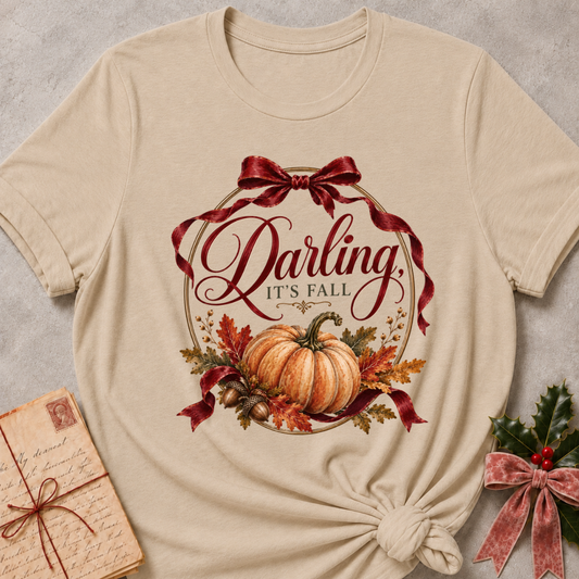 Heather stone women's relaxed tee with a vintage Darling It's Fall script design framed by a gold wreath, a burgundy ribbon bow, and a harvest pumpkin