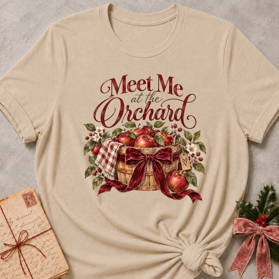 Heather Stone relaxed fit tee with Meet Me at the Orchard lettering, a harvest basket of red apples, blossoms and a burgundy bow