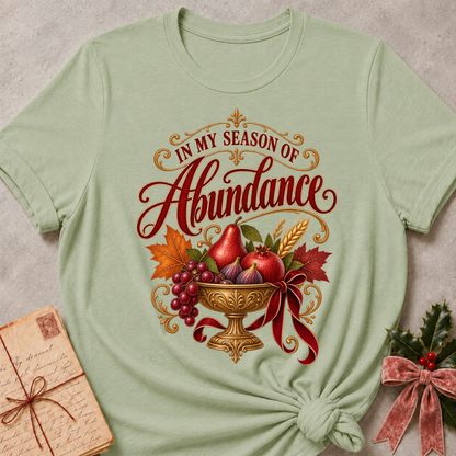 Maroon relaxed fit tee with In My Season of Abundance script and an ornate golden bowl of pears, pomegranates, figs, grapes and wheat with a ruby bow