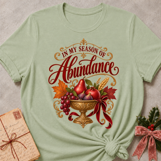 Maroon relaxed fit tee with In My Season of Abundance script and an ornate golden bowl of pears, pomegranates, figs, grapes and wheat with a ruby bow