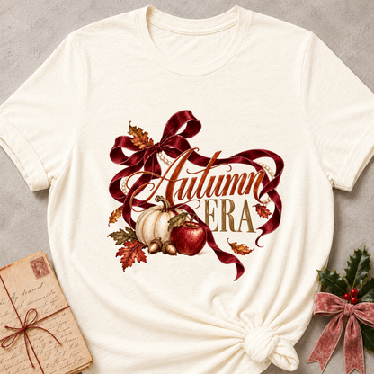 Natural cream women's relaxed tee with Autumn Era script framed by a burgundy ribbon, pearls, a cream pumpkin, a red apple, and fall leaves