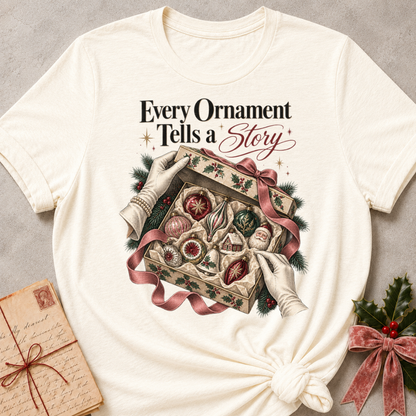 Natural relaxed fit tee with Every Ornament Tells a Story lettering, gloved hands lifting the lid on a keepsake box of vintage ornaments