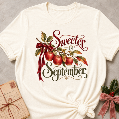 Natural relaxed fit tee with Sweeter in September script lettering, an apple branch with red apples, autumn leaves and a burgundy bow