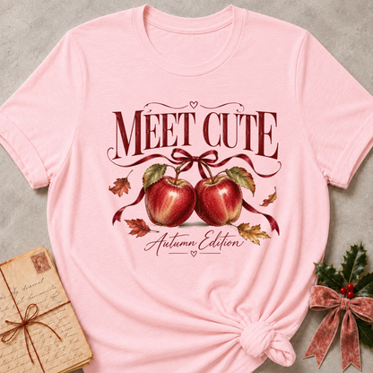 Pink relaxed fit tee with Meet Cute Autumn Edition lettering, two red apples and a burgundy bow