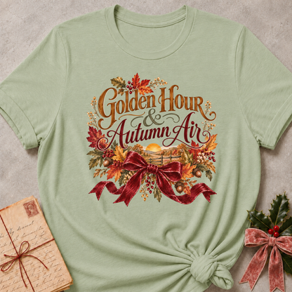 Sage relaxed fit tee with Golden Hour and Autumn Air lettering, a sunset over a wooden fence, fall leaves and a burgundy bow