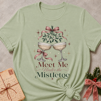 Sage relaxed fit tee with Meet Me Under the Mistletoe lettering, two champagne coupes, blush bows and a sprig of mistletoe