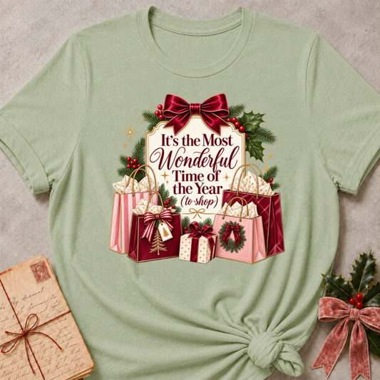 Sage relaxed fit tee with It's the Most Wonderful Time of the Year to Shop lettering, a burgundy velvet bow, holly and stacked gift bags