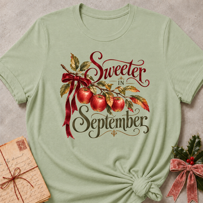 Sage relaxed fit tee with Sweeter in September script lettering, an apple branch with red apples, autumn leaves and a burgundy bow