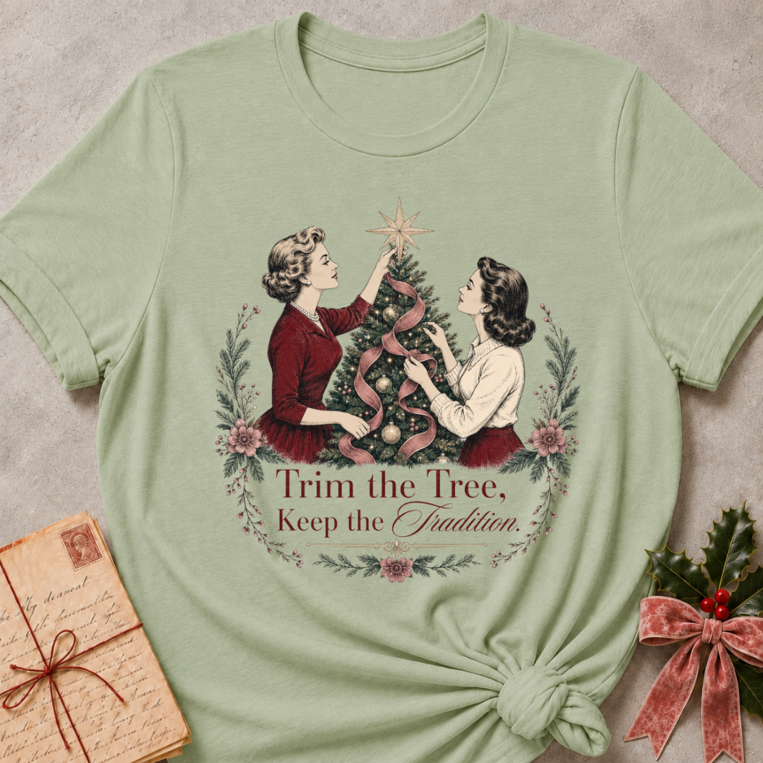 Sage green relaxed fit tee with two vintage women trimming a Christmas tree and Trim the Tree Keep the Tradition lettering