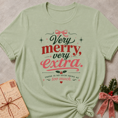 Sage relaxed fit tee with Very Merry, Very Extra retro lettering, a pink bow, holly and scattered stars
