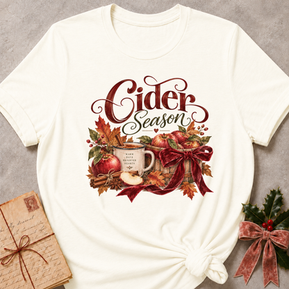Vintage white women's relaxed tee with a Cider Season script design with a cider mug, red apples, cinnamon sticks, and a burgundy ribbon bow