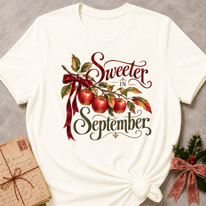 Vintage White relaxed fit tee with Sweeter in September script lettering, an apple branch with red apples, autumn leaves and a burgundy bow
